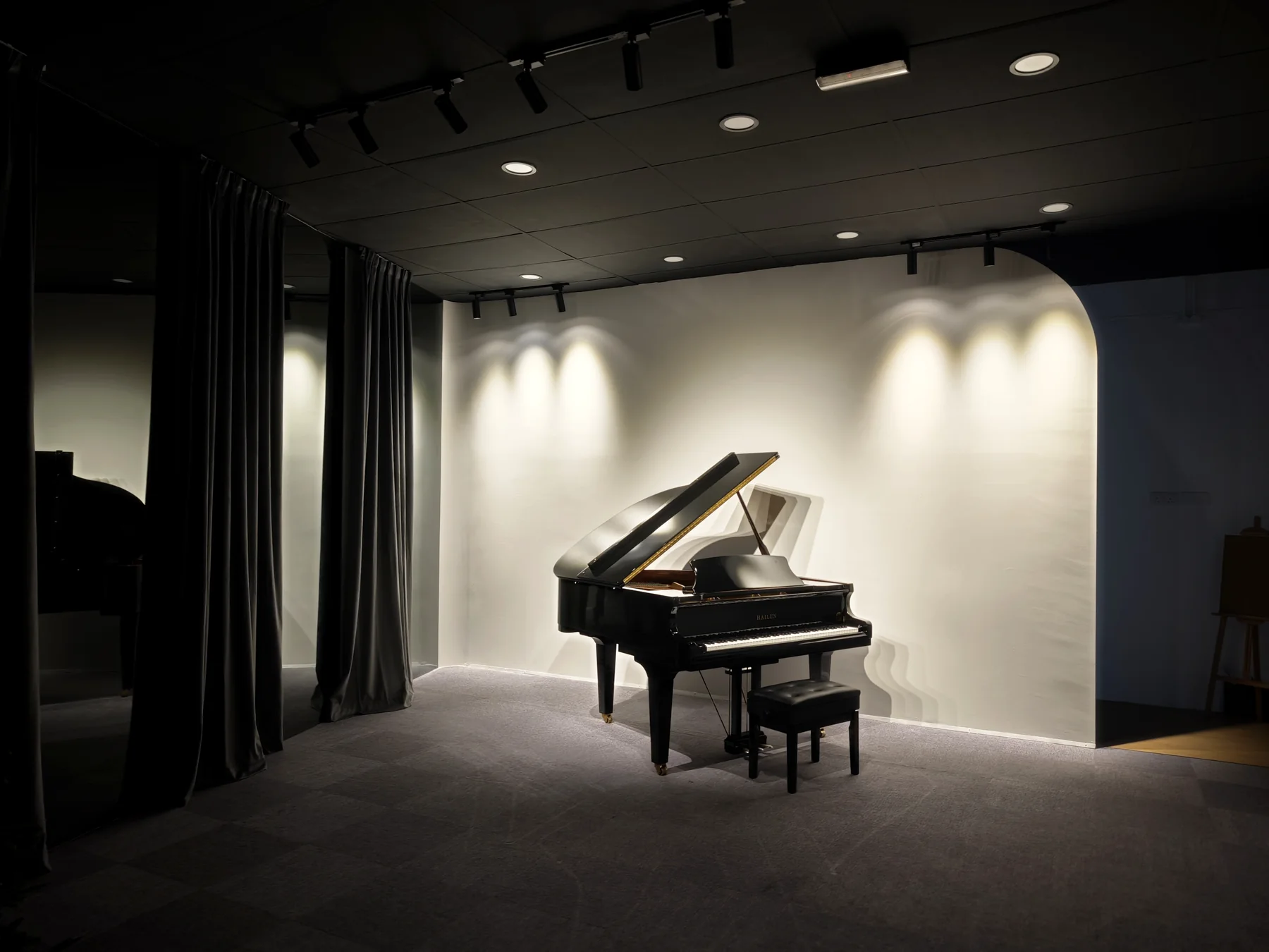 Expressivo recital space with a grand piano under stage lighting