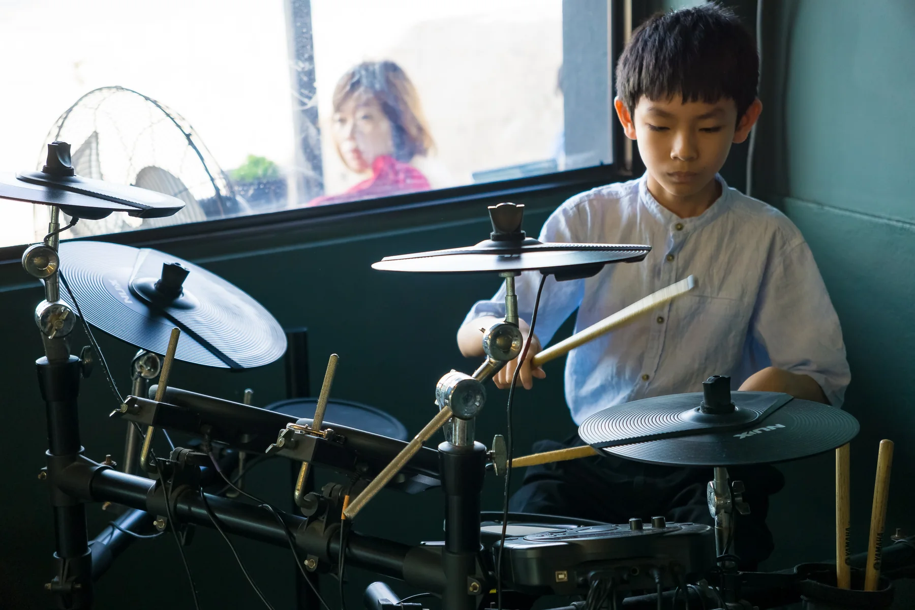 Young student playing an electronic drum kit at an Expressivo event